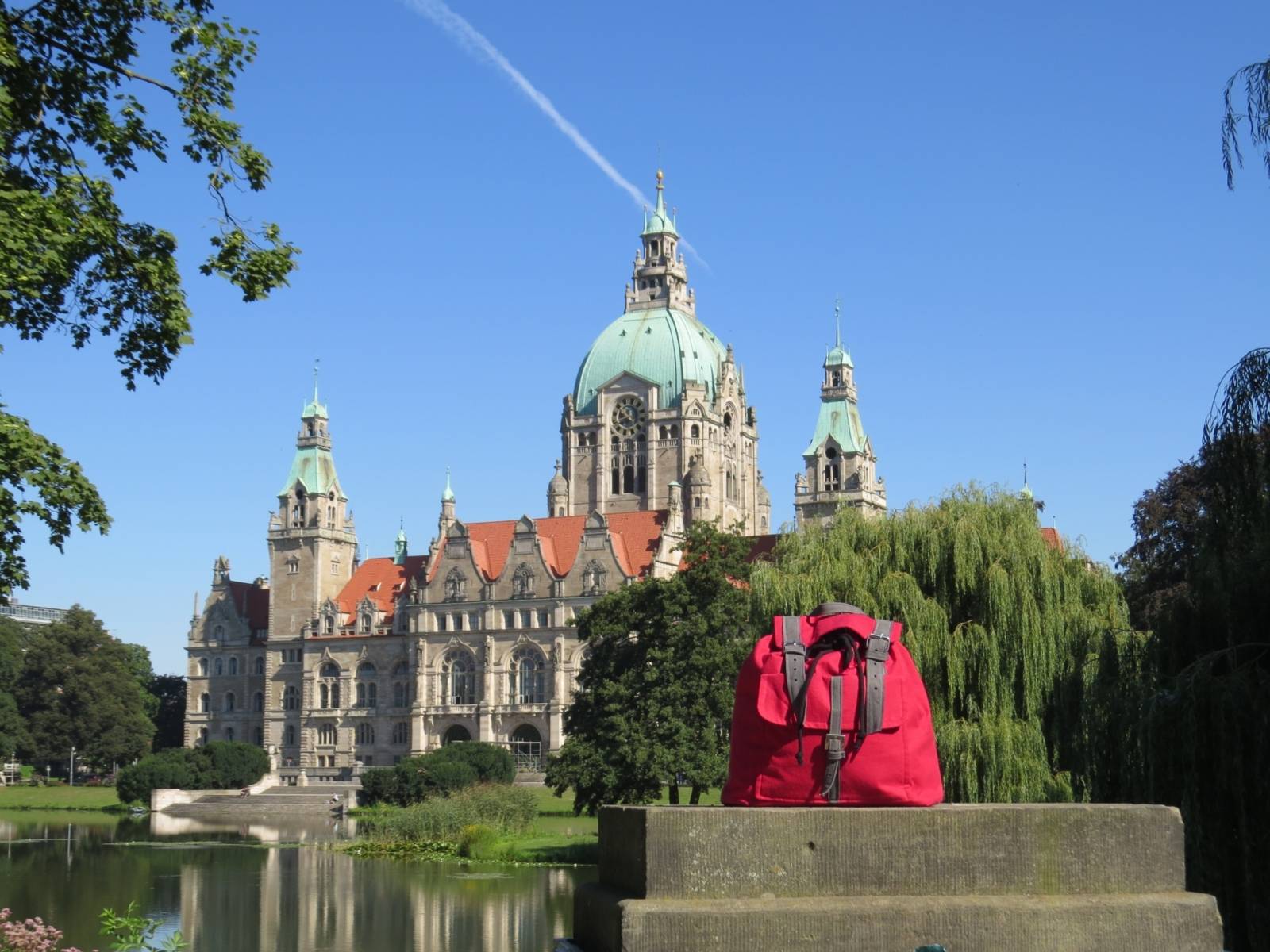 Das neue Rathaus in Hannover, Foto aufgenommen aus Richtung des Maschparks. Im Vordergrund steht ein roter Rucksack.